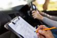 Clipboard with driving test and instructor writing in pencil. 